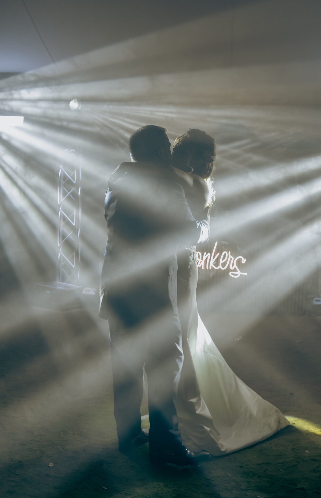 Beso de los novios entre haces de luz durante el baile